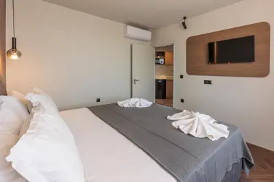 a bedroom with a white bed with a tv on the wall at Hotel Sea Sand in Sveti Vlas