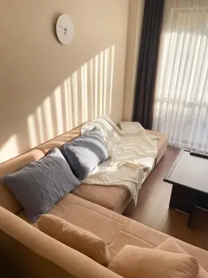 a couch in a living room with a clock on the wall at Cozy apartment on Sunny Beach in Sunny Beach