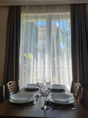 a table with plates and wine glasses in front of a window at Messembria Palace in Sunny Beach
