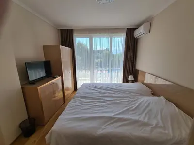 a bedroom with a white bed and a television at Messembria Palace in Sunny Beach