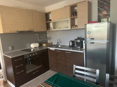 a kitchen with wooden cabinets and a stainless steel refrigerator at Kalia A7 Sunny Beach in Bŭnzareto