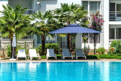 a pool with chairs and an umbrella and palm trees at Apartment D9 Yassen HV in Sunny Beach