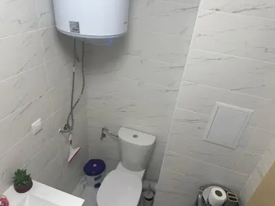 a white bathroom with a toilet and a water tank at Kalia A7 Sunny Beach in Sunny Beach