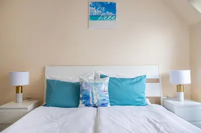 a bedroom with a bed with blue pillows and two lamps at ViolaSuite in Varna South Bay by RV Apartments in Varna City