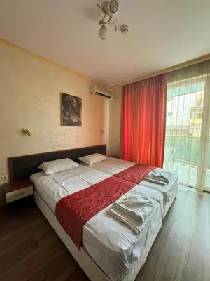 a bedroom with a large bed with a red curtain at HOLIDAY Suites at Sunny Beach in Sunny Beach
