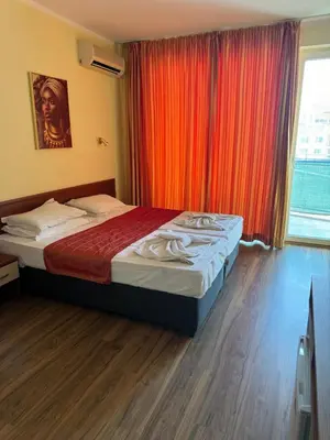 a bedroom with a bed with an orange curtain at HOLIDAY Suites at Sunny Beach in Sunny Beach
