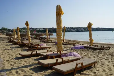 a row of lounge chairs and umbrellas on a beach at Six bedroom luxury villa with private pool in quiet residential area near beaches in Sozopol