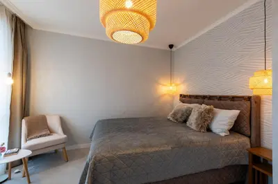 a bedroom with a bed and a chair and a chandelier at Spirit apartment in Burgas City