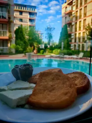 a plate of food with toast and bread with a pool at All-inclusive Holiday Apartments in Tarsis Hotel & Aquapark in Sunny Beach