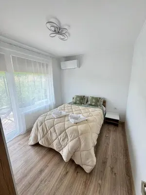 a white bedroom with a bed and a window at Sea apartment in Burgas City