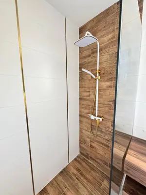 a shower in a bathroom with a wooden wall at Sea apartment in Burgas City