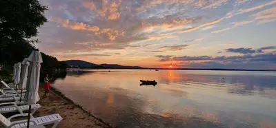 a boat in the water at sunset on a beach at Eve Santa Marina Sea View Apartment - sea, pools, relax in Sozopol