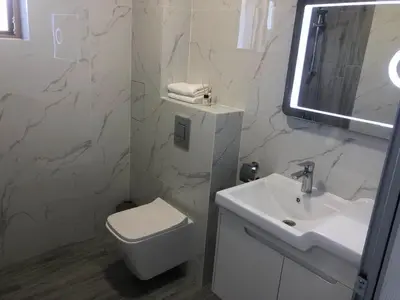 a white bathroom with a toilet and a sink at Blue Magenta 1 in Sozopol