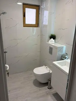 a white bathroom with a toilet and a sink at Blue Magenta 1 in Sozopol