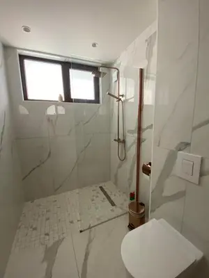 a bathroom with a shower with a toilet and a window at Luxurious house Sarafovo beach in Burgas City
