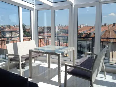 a glass table and chairs on a balcony with a view at Burgas Center in Burgas City
