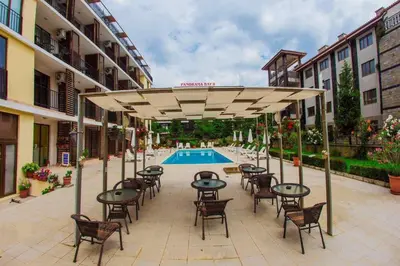 a patio with tables and chairs and a pool at Студио до плажа Свети Влас in Sveti Vlas