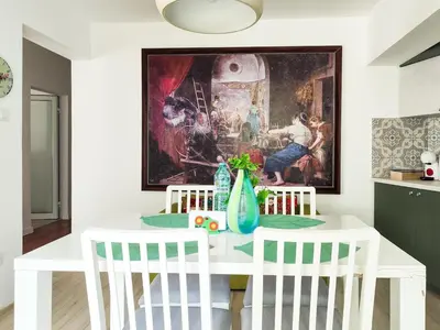 a white dining room table with white chairs and a painting at The Puzzle in Varna City