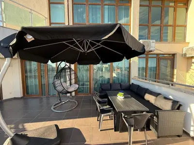a black umbrella on a patio with a table and chairs at YS Platinum Residence in Sunny Beach