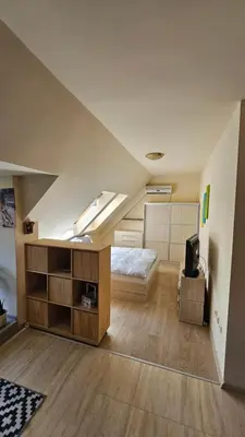 an attic bedroom with a bed and a tv at Уютно студио до центъра на Бургас in Burgas City
