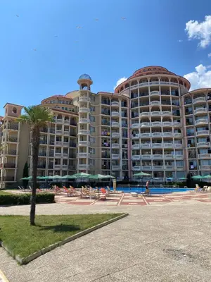 a large apartment building with a palm tree in front of it at ANDALUSIA BEACH A602 Elenite in Burgas City
