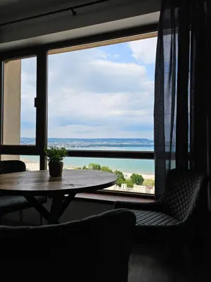 a room with a table and a view of the water at Comfy Flat Sea View & Strong Wi-Fi in Varna City