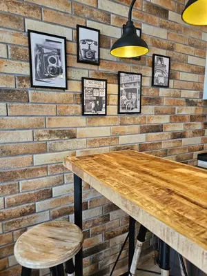 a brick wall with a wooden table and stools at Comfy Flat Sea View & Strong Wi-Fi in Varna City