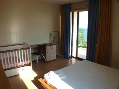 a bedroom with a bed and a desk with a crib at Nessebar View Apartament in Nesebar