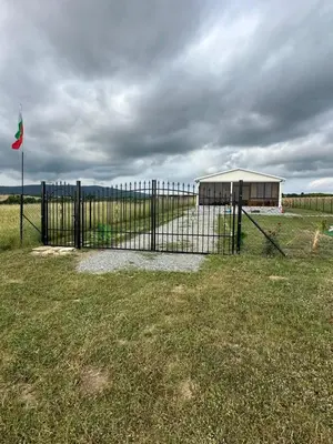 a fence with a gate in a field with a building at Морски Бриз in Lozenets