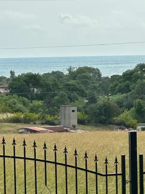 a fence in front of a field with the ocean at Морски Бриз in Lozenets