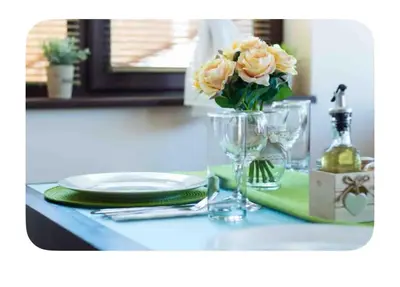 a table with a glass vase with flowers on it at Guesthouse Christina in Varna City
