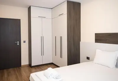 a bedroom with a white bed and a cabinet at Exclusive Central Varna Apartment - 2 Beds and Parking by Flat Mаnаger in Varna City