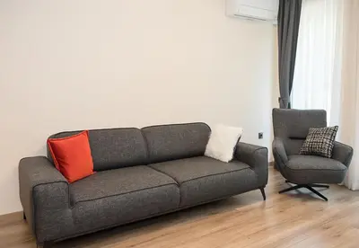 a couch and a chair in a living room at Exclusive Central Varna Apartment - 2 Beds and Parking by Flat Mаnаger in Varna City