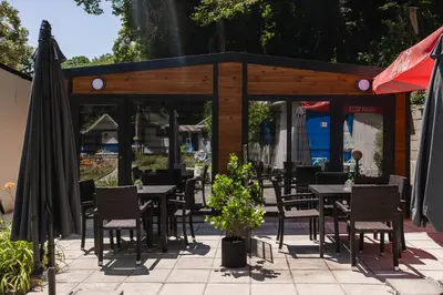 a restaurant with tables and chairs and an umbrella at Къмпинг- бунгала Албатрос in Varna City