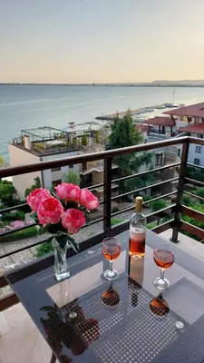 a table with two wine glasses and flowers on a balcony at Dolce Vita 1 Ap-6 in Sveti Vlas