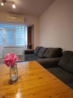 a living room with a vase of flowers on a wooden table at Accommodation apartment MARGARITA in Burgas City