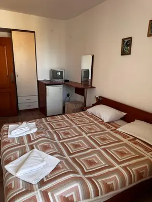 a hotel room with a large bed and a desk at Benadi Guest House in Burgas City