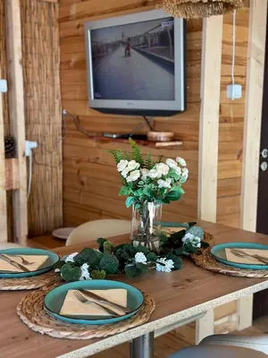 a wooden table with plates and a vase of flowers at Каравана Бамбоо in Sozopol