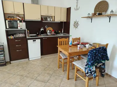 a kitchen with a wooden table with chairs and a table at Grand Kamelia C1 in Sunny Beach