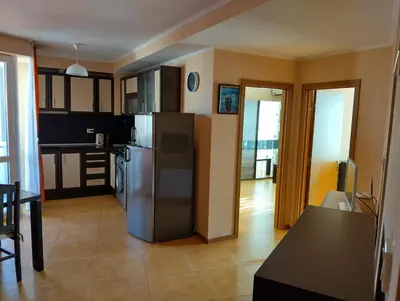 a kitchen with a stainless steel refrigerator and a table at Отдых in Sunny Beach
