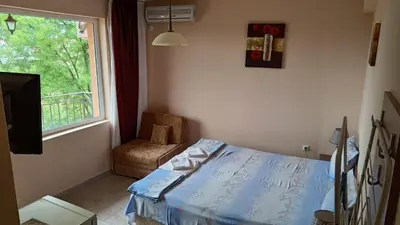 a bedroom with a bed and a window and a chair at Вила Фернандес in Chernomorets