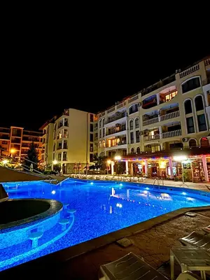a large swimming pool with blue lighting in front of buildings at Royal Dreams apartments - 2 in Sunny Beach