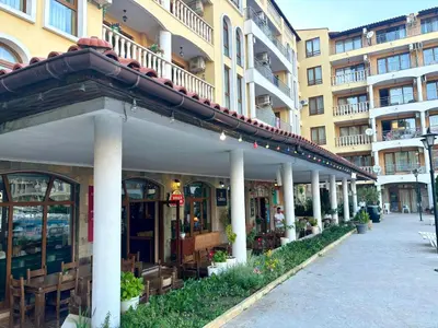 a building with tables and chairs on a street at Royal Dreams apartments - 2 in Sunny Beach