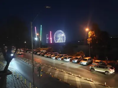 a bunch of cars parked in a parking lot with a ferris wheel at Marina's Flat in Varna City