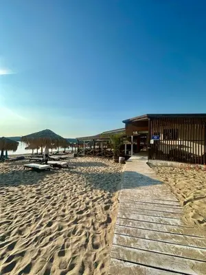 a beach with straw umbrellas and chairs on the sand at Complex Gallery Saint Thomas in Sozopol
