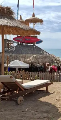 a beach with a bench and a straw umbrella at РАВДА Лазур Аурелия in Ravda