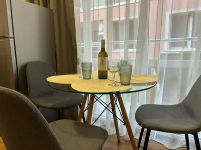 a table with a bottle of wine and glasses on it at Судио Диксан in Pomorie