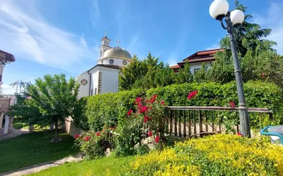 a building with a clock tower with a fence and flowers at Ela, Kedar 3 in Sveti Vlas