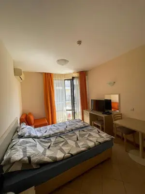 a bedroom with a bed and a desk and a television at Royal Sun SP apartments in Sunny Beach
