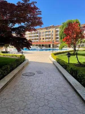 a walkway in a park with a large building at Royal Sun SP apartments in Sunny Beach